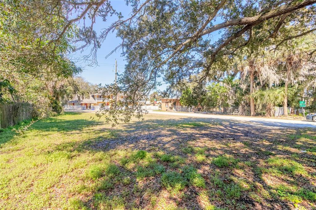 A grassy, partially shaded vacant lot sits in front of a multi-story apartment building — 124 DIMMICK STREET, NEW SMYRNA BEACH, FL
