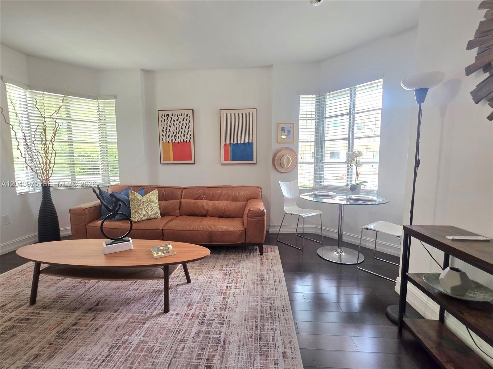 A living room features a brown leather sofa, oval coffee table, and a small dining area — 601 11th St # 107, Miami Beach FL 33139, MIAMI BEACH, FL
