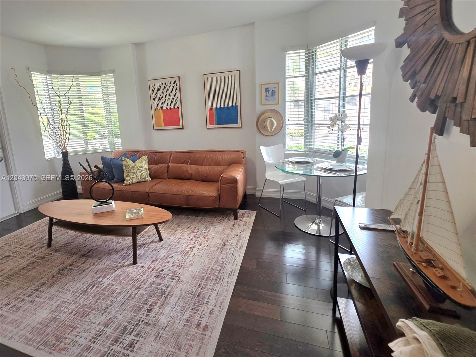 A living room features a brown leather sofa, wood floors, and a glass dining table — 601 11th St # 107, Miami Beach FL 33139, MIAMI BEACH, FL