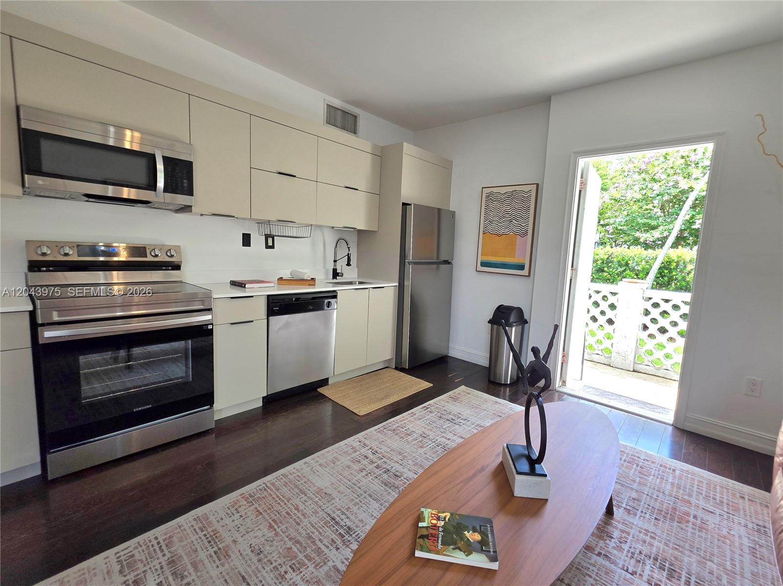 A modern kitchen with stainless steel appliances and light cabinetry opens to a private patio — 601 11th St # 107, Miami Beach FL 33139, MIAMI BEACH, FL