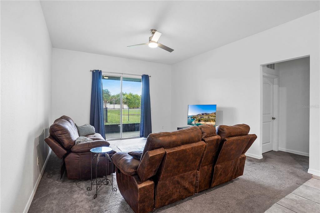 A living room features brown leather reclining furniture, a ceiling fan, and sliding glass doors — 2052 EMERALD SPRINGS DRIVE, APOPKA, FL