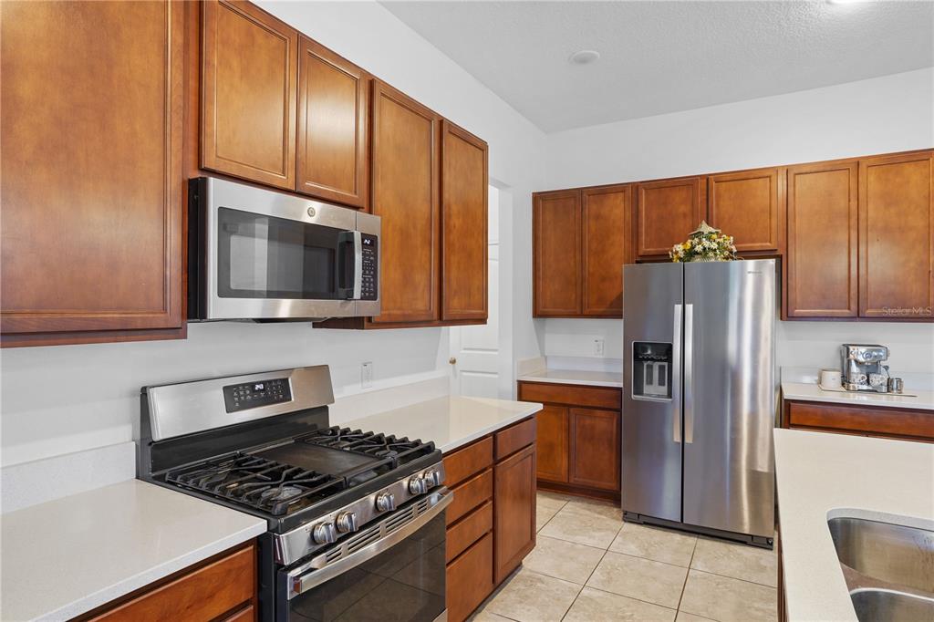 A kitchen with wood cabinets, stainless steel appliances, and light-colored countertops — 2052 EMERALD SPRINGS DRIVE, APOPKA, FL