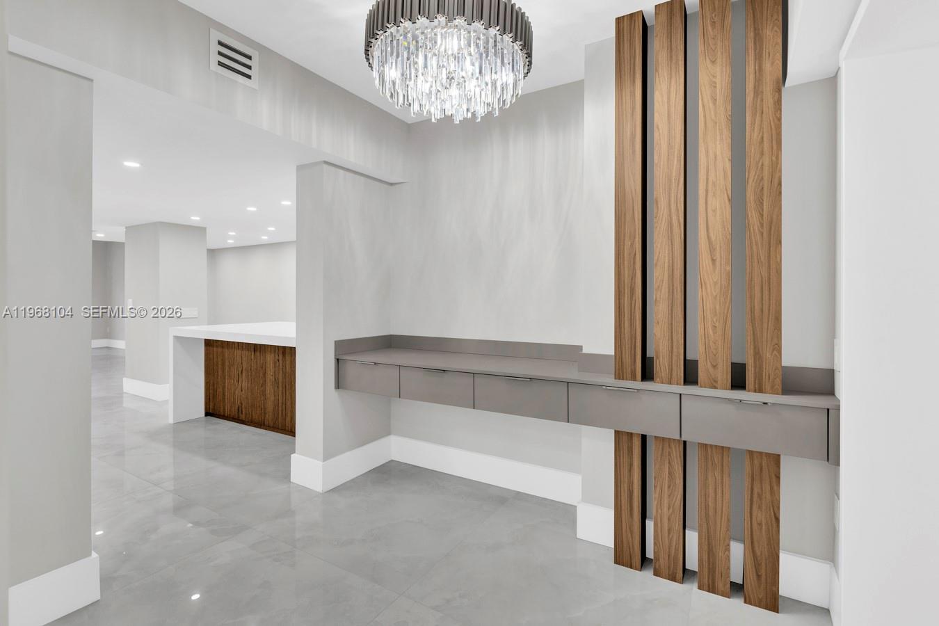 A modern hallway features a floating gray console, wood slat wall accents, and a chandelier — 2051 SE 3rd St # 406, Deerfield Beach FL 33441, DEERFIELD BEACH, FL