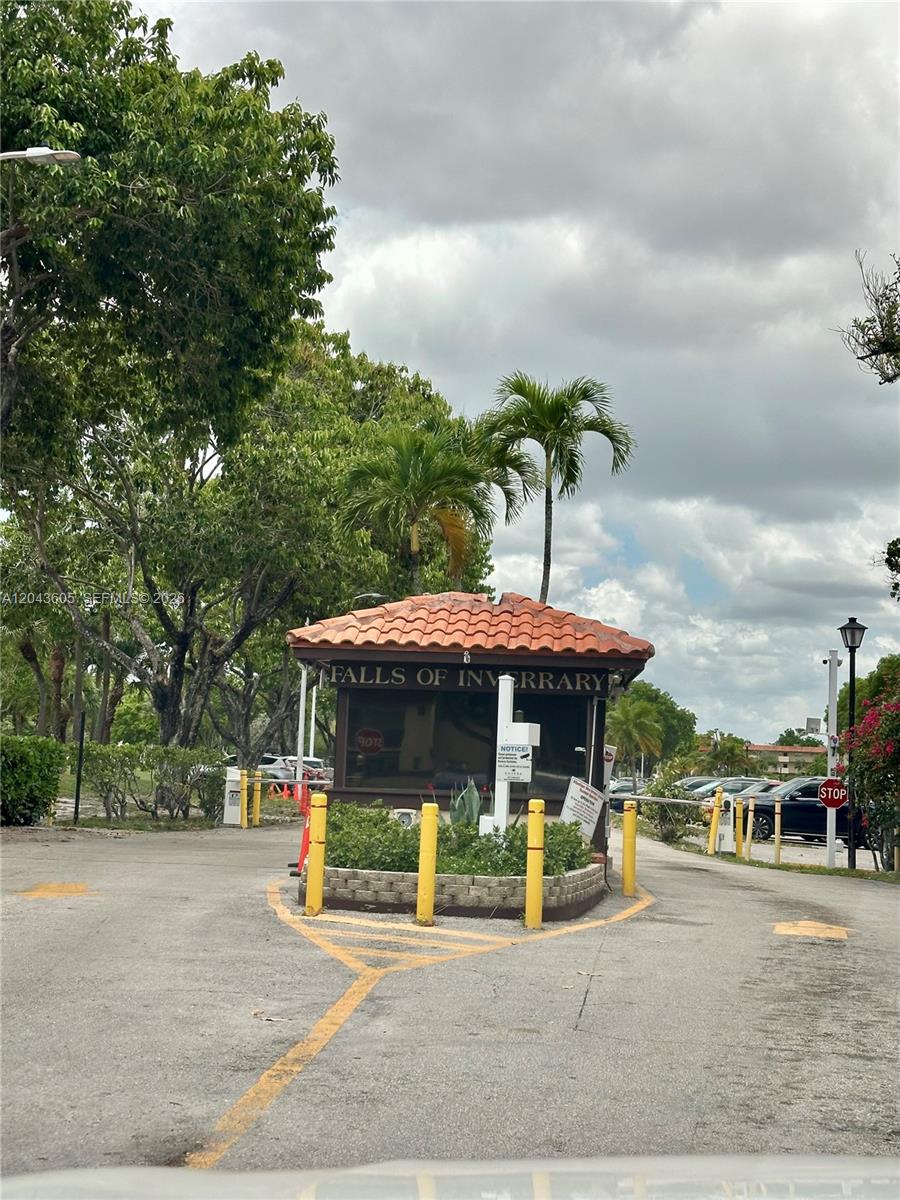 A gated entrance with a guardhouse and a tile roof under a cloudy sky — 6201 N Falls Cir Dr # 212, Lauderhill FL 33319, LAUDERHILL, FL
