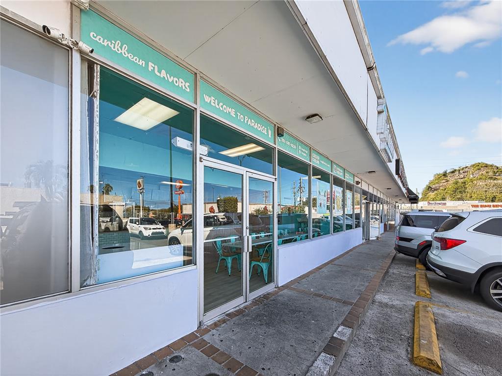 The exterior of a Caribbean Flavors restaurant storefront features glass windows and a sidewalk — Calle 24 URB SIERRA BAYAMON, BAYAMON, PR