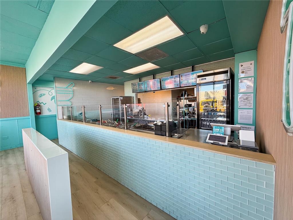 A commercial food service counter features light blue subway tile, wood-look flooring, and menu boards — Calle 24 URB SIERRA BAYAMON, BAYAMON, PR