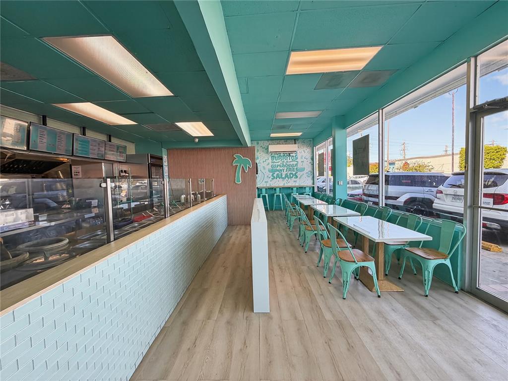A brightly lit restaurant interior features light wood floors, teal walls, and metal dining chairs — Calle 24 URB SIERRA BAYAMON, BAYAMON, PR