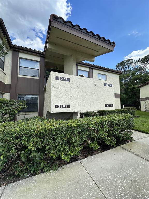 An exterior view of a multi-story apartment building with a stucco facade and landscaping — 3269 WESTRIDGE BOULEVARD UNIT 103, ORLANDO, FL