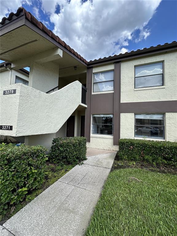 A two-story stucco apartment building features a concrete staircase and a paved walkway — 3269 WESTRIDGE BOULEVARD UNIT 103, ORLANDO, FL
