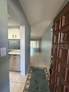 A view from an entryway looking toward a kitchen with white cabinets and tiled floors — 3269 WESTRIDGE BOULEVARD UNIT 103, ORLANDO, FL