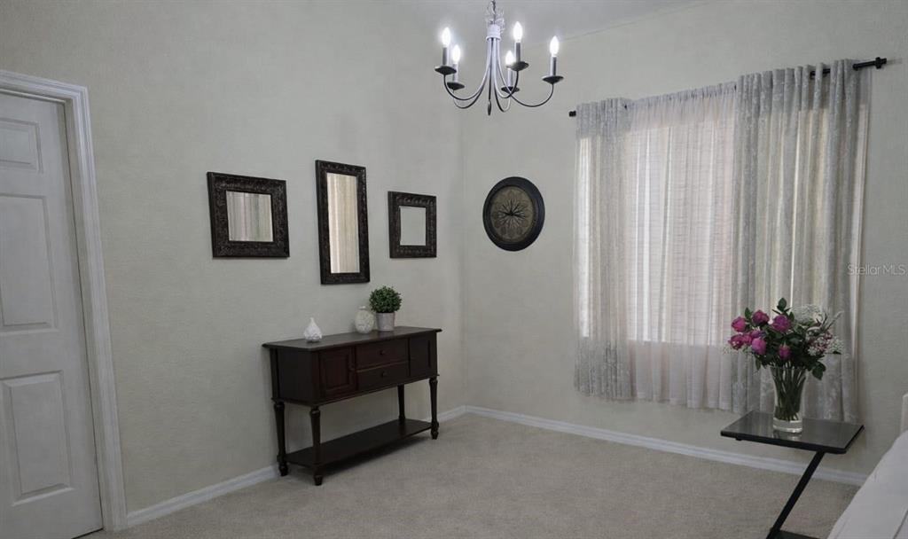 A carpeted dining area features a chandelier, an arched doorway, and an adjacent kitchen — 439 CARAWAY DRIVE, KISSIMMEE, FL