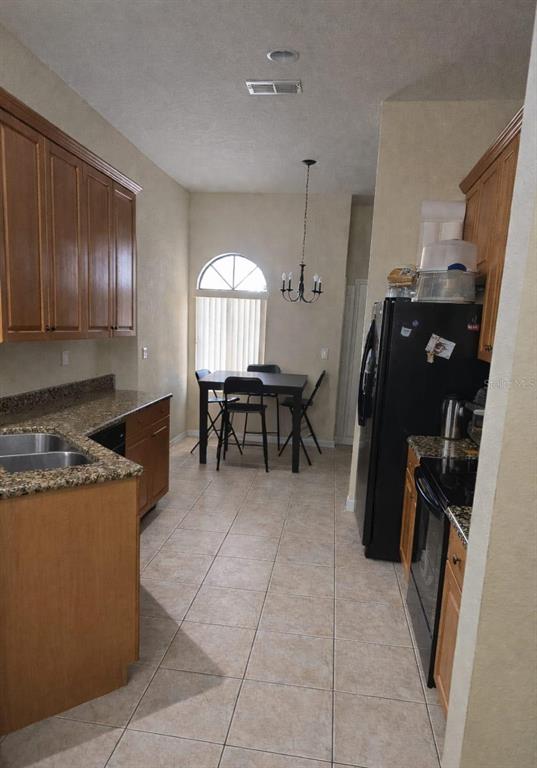 An empty living room features beige carpet, tan walls, and a sliding glass door — 439 CARAWAY DRIVE, KISSIMMEE, FL