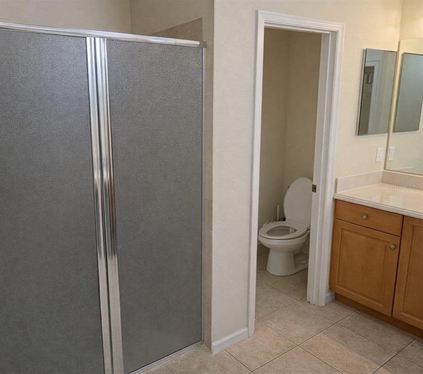 An empty living room features beige walls, tan carpeting, and an arched doorway — 439 CARAWAY DRIVE, KISSIMMEE, FL