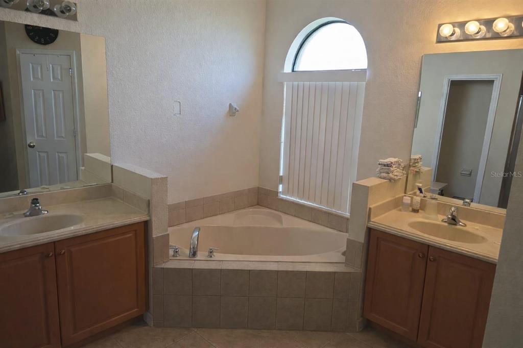 An empty bedroom features beige walls, tan carpeting, and an arched window with vertical blinds — 439 CARAWAY DRIVE, KISSIMMEE, FL