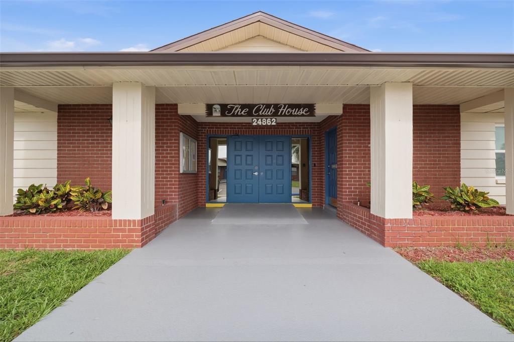The exterior of a brick building features a covered entrance with double blue doors — 24862 US HIGHWAY 19 N UNIT 1705, CLEARWATER, FL