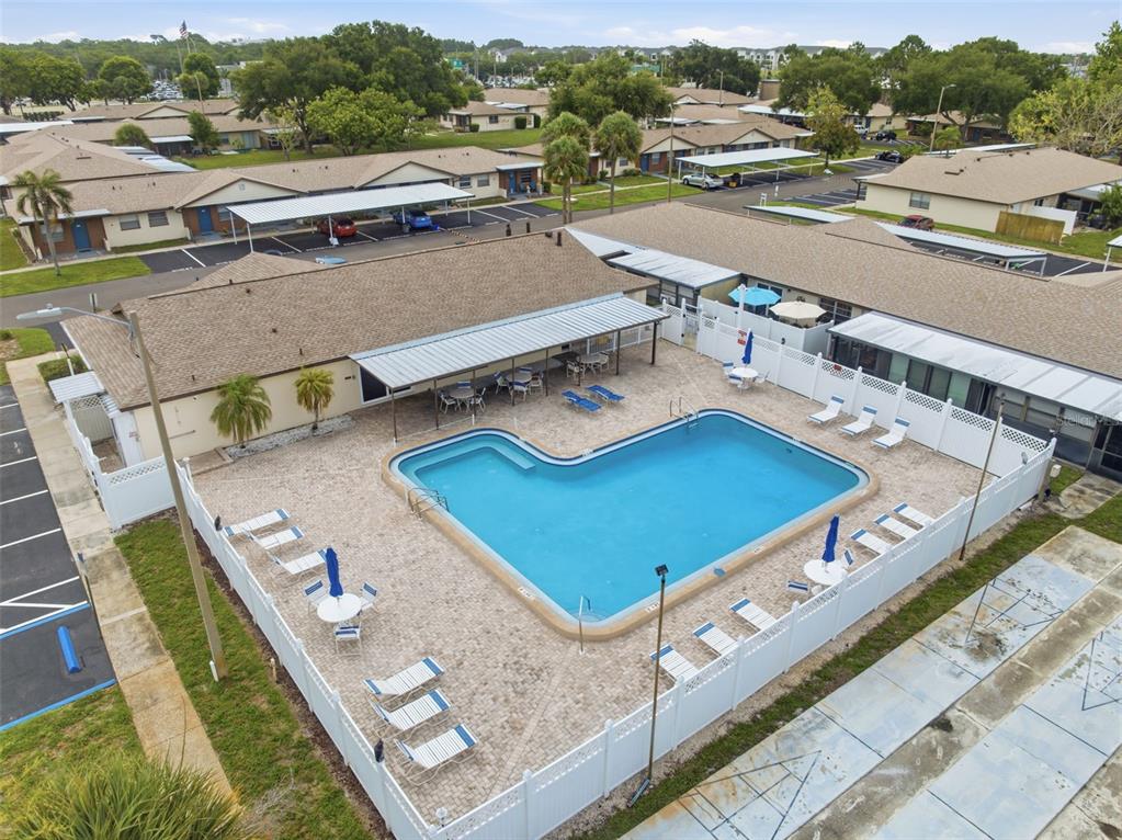 An aerial view shows an L-shaped swimming pool surrounded by a patio and white fencing — 24862 US HIGHWAY 19 N UNIT 1705, CLEARWATER, FL