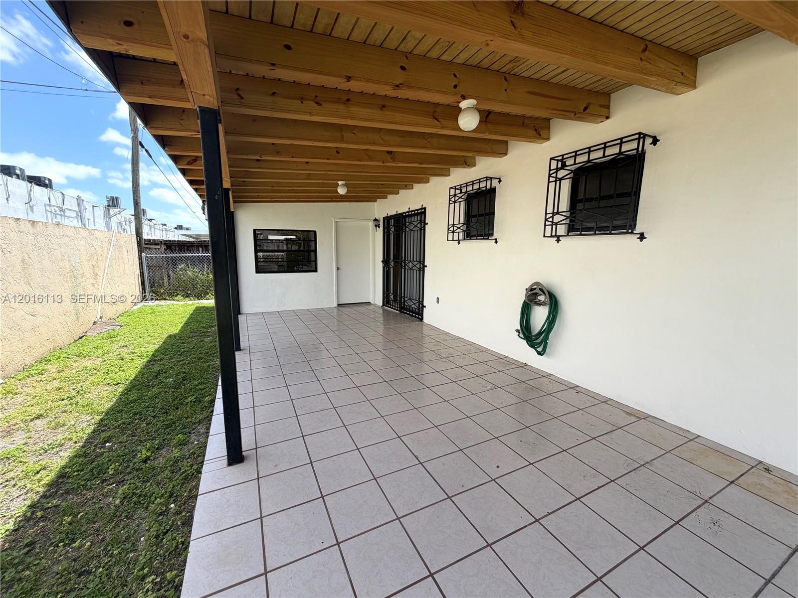 A covered patio features a tiled floor, wooden ceiling beams, and white exterior walls — 7993 SW 9th Ter, Miami FL 33144, MIAMI, FL