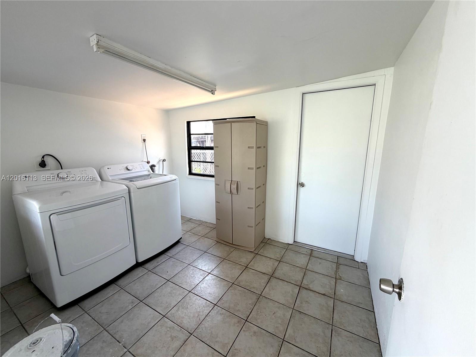 A laundry room features white appliances, a beige storage cabinet, and tiled flooring — 7993 SW 9th Ter, Miami FL 33144, MIAMI, FL