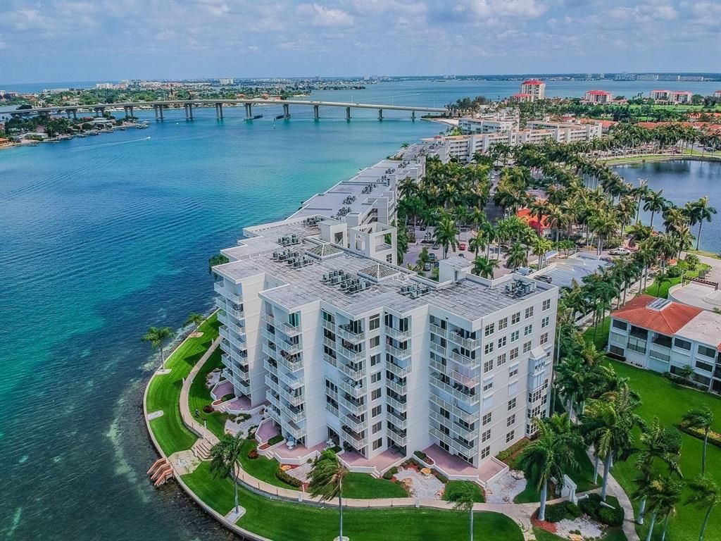 An aerial view shows a multi-story white apartment building situated on a waterfront peninsula — 6105 BAHIA DEL MAR CIRCLE UNIT 382, ST PETERSBURG, FL