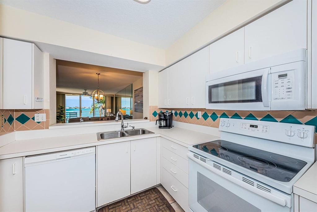 A white kitchen features a pass-through window with a view of the water — 6105 BAHIA DEL MAR CIRCLE UNIT 382, ST PETERSBURG, FL