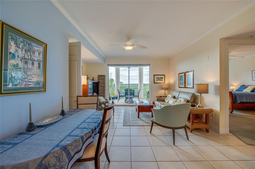 An open-concept living and dining area with tile floors, a balcony, and a bedroom view — 4624 HARBOUR VILLAGE BOULEVARD UNIT 4504, PONCE INLET, FL