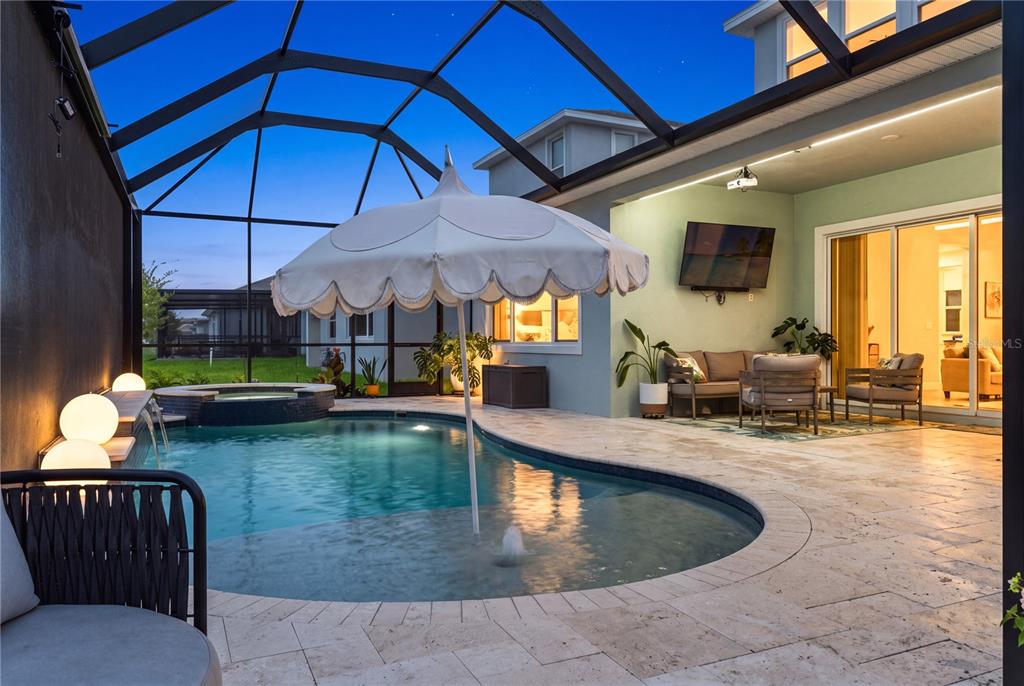 A screened-in patio features a swimming pool with a fountain, a hot tub, and furniture — 8761 DRUMMER PLANK DRIVE, WESLEY CHAPEL, FL