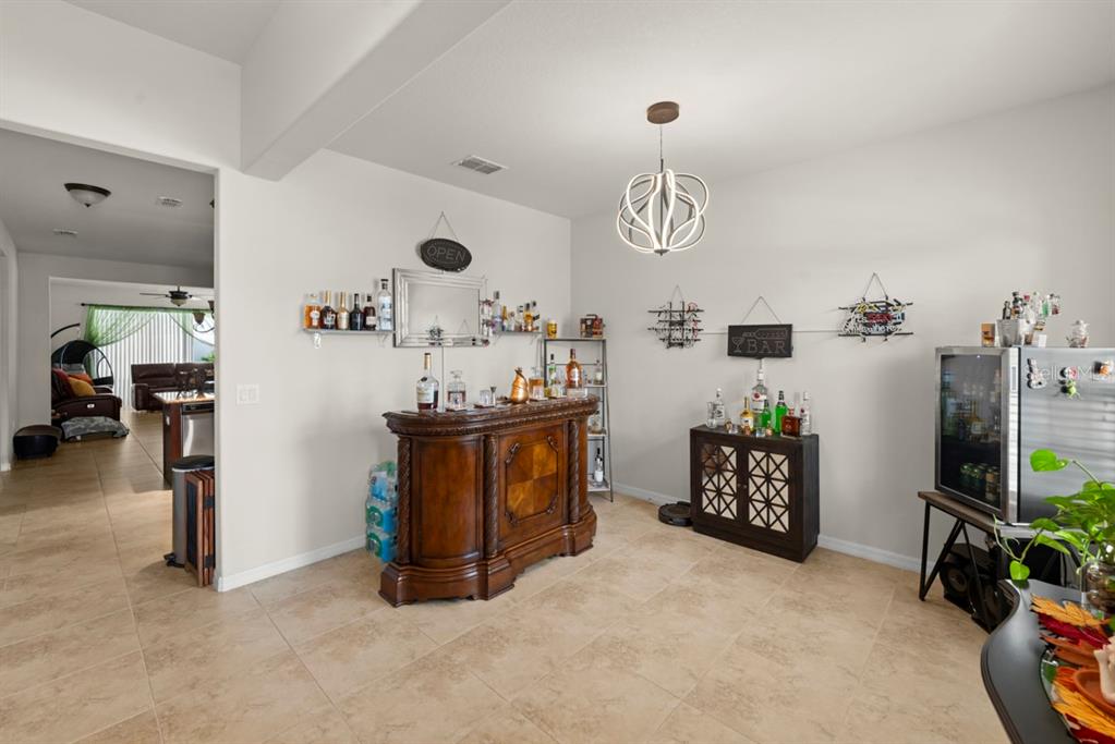 A home bar area features a wooden bar, a cabinet, and a modern pendant light — 2542 FOLIO WAY, KISSIMMEE, FL