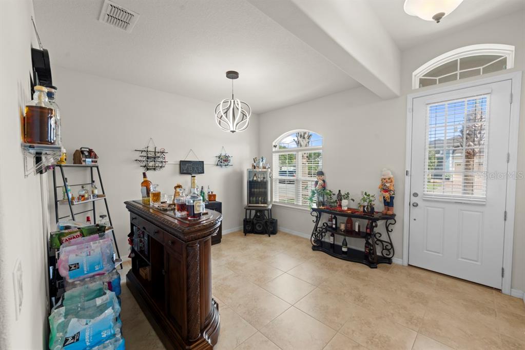 A home bar area features a wooden bar, a beverage cooler, and tile flooring — 2542 FOLIO WAY, KISSIMMEE, FL
