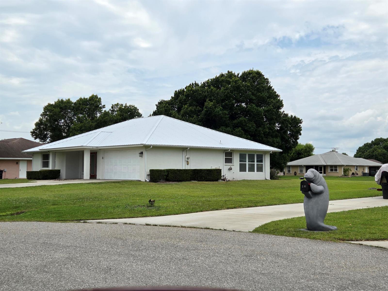 A white single-story house with a metal roof and a manatee-shaped mailbox in front — 2321 SW 3rd Court, Okeechobee FL 34974, OKEECHOBEE, FL