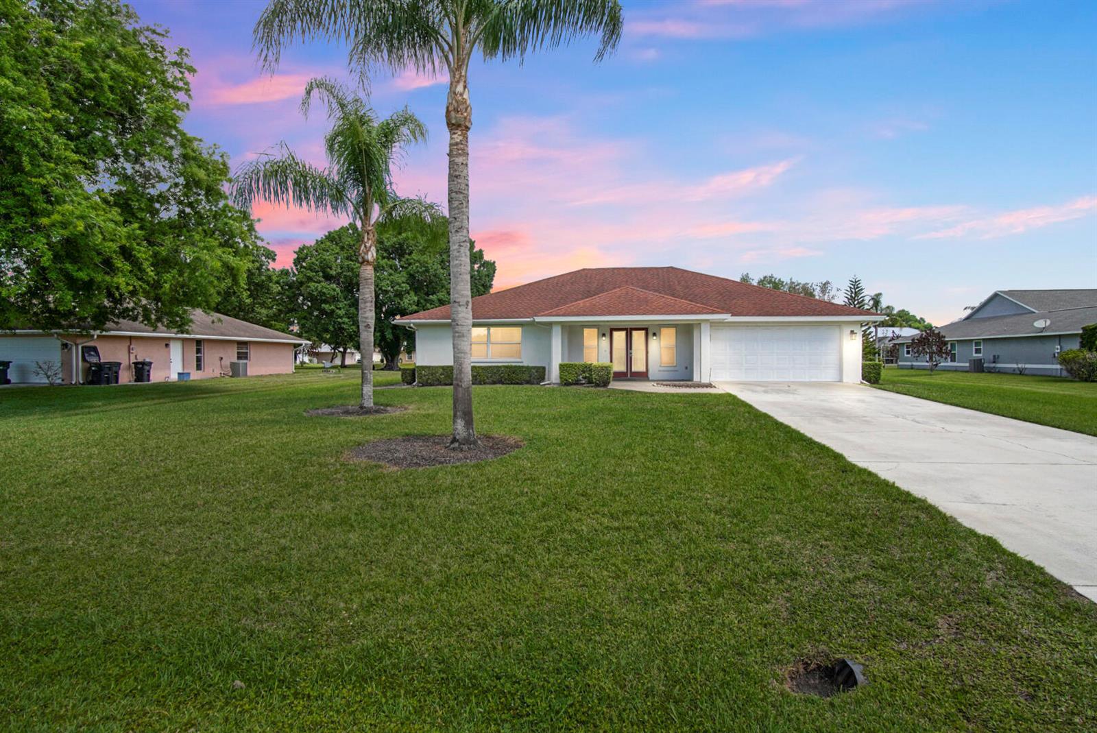 A single-story house with a white exterior, a red roof, and a concrete driveway — 2321 SW 3rd Court, Okeechobee FL 34974, OKEECHOBEE, FL
