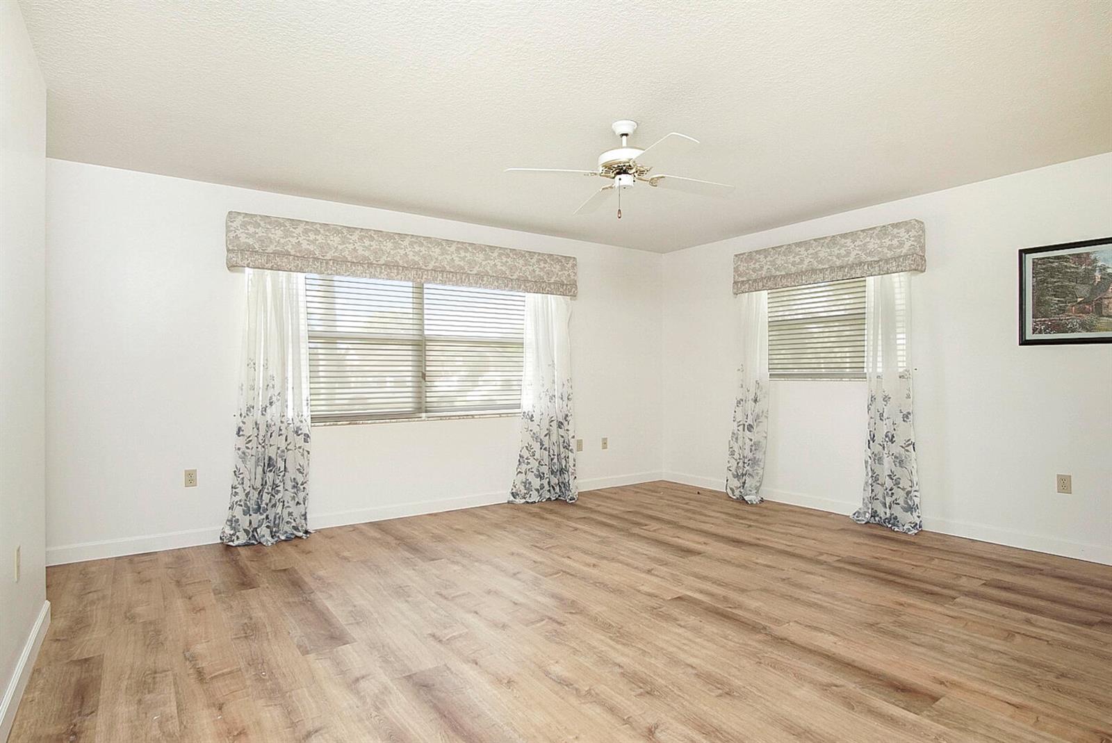 An empty bedroom features light wood-look flooring, white walls, and two windows with valances — 2321 SW 3rd Court, Okeechobee FL 34974, OKEECHOBEE, FL