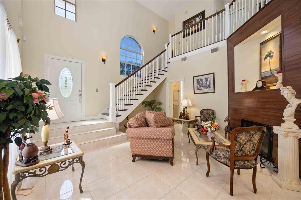 A high-ceilinged foyer features a staircase, tile flooring, a fireplace, and traditional furniture — 1621 DR MARTIN LUTHER KING WAY, SARASOTA, FL