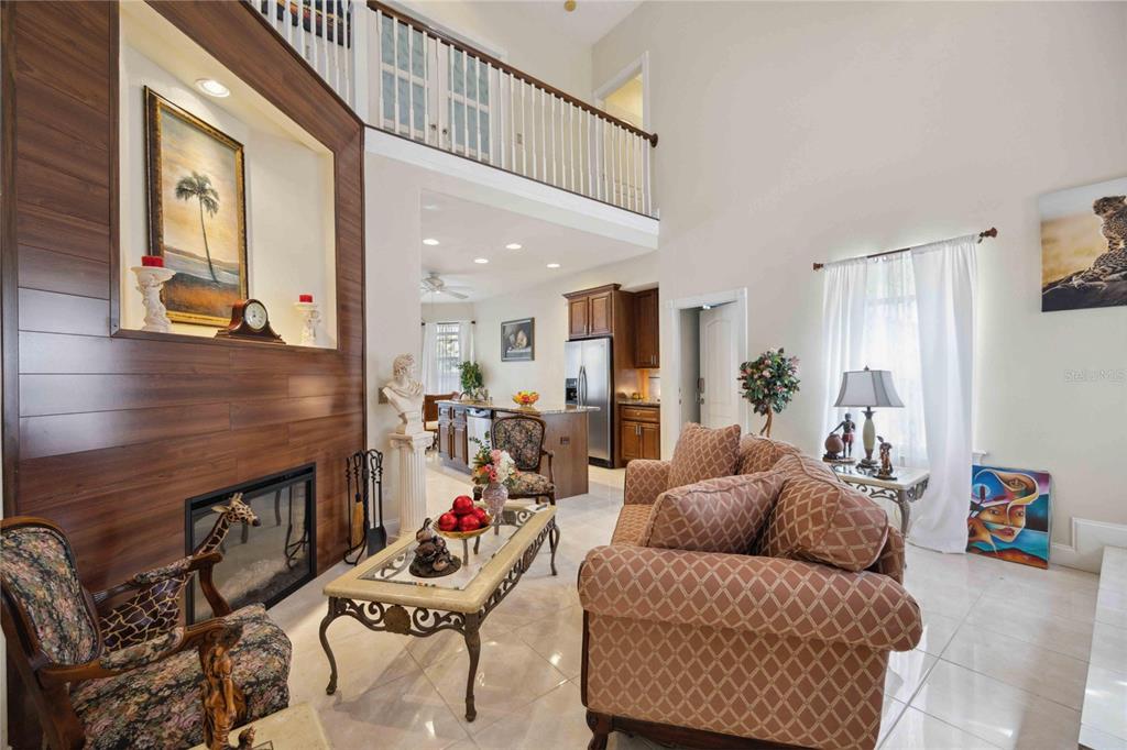 A living room with a fireplace, wood-paneled wall, and an open view to the kitchen — 1621 DR MARTIN LUTHER KING WAY, SARASOTA, FL