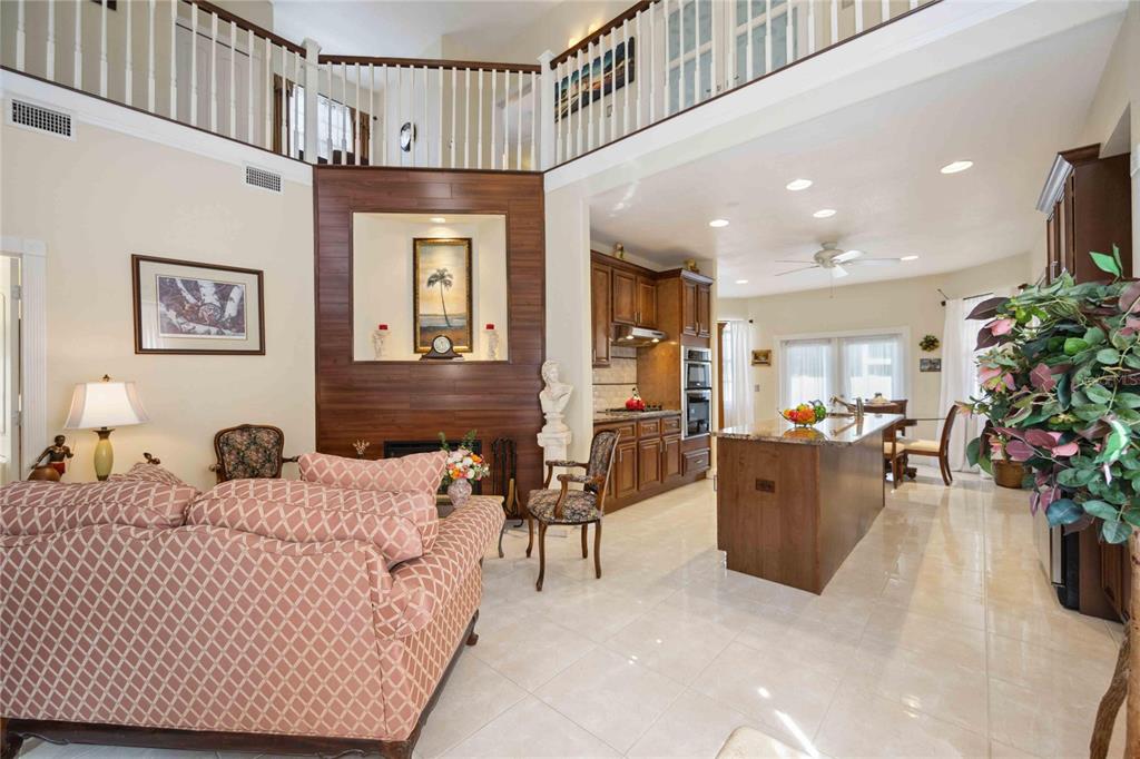 A living room with a fireplace and wood accent wall opens to a kitchen area — 1621 DR MARTIN LUTHER KING WAY, SARASOTA, FL