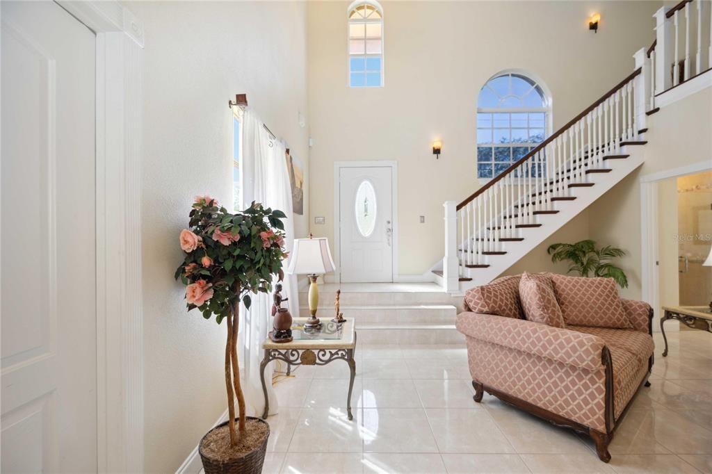 A bright foyer features a staircase, tile flooring, a potted plant, and a patterned sofa — 1621 DR MARTIN LUTHER KING WAY, SARASOTA, FL