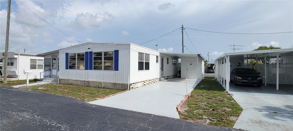 A white mobile home with blue shutters, a carport, and a paved driveway — 7490 46TH AVENUE N UNIT 314, ST PETERSBURG, FL