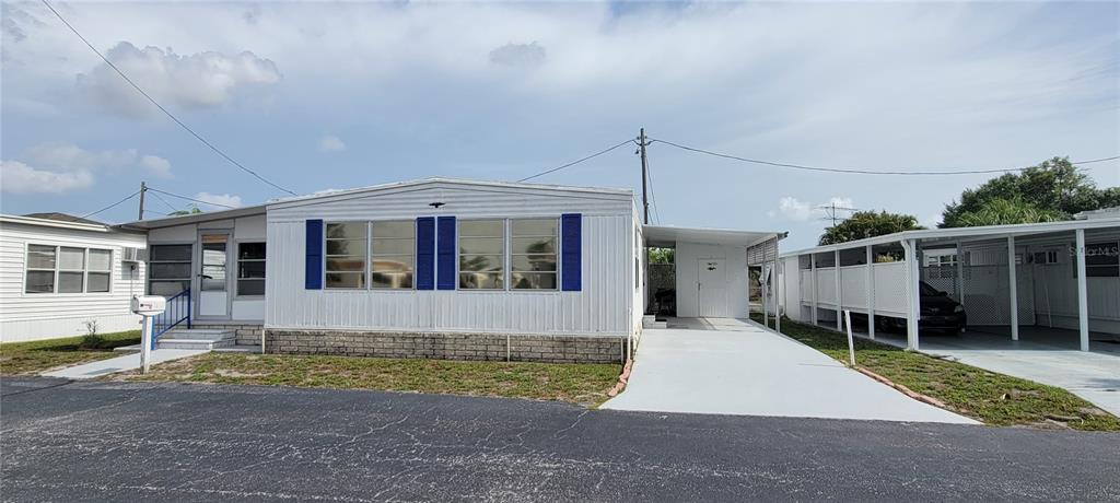 A white manufactured home with blue shutters, a carport, and a paved driveway — 7490 46TH AVENUE N UNIT 314, ST PETERSBURG, FL