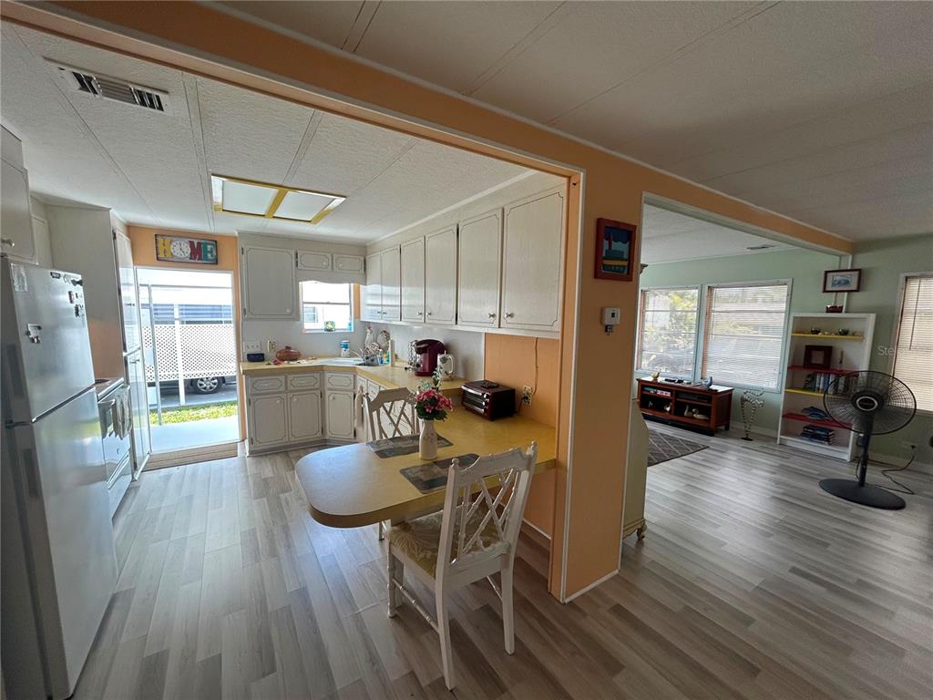 A kitchen with white cabinets and a yellow countertop features an attached dining table — 7490 46TH AVENUE N UNIT 314, ST PETERSBURG, FL