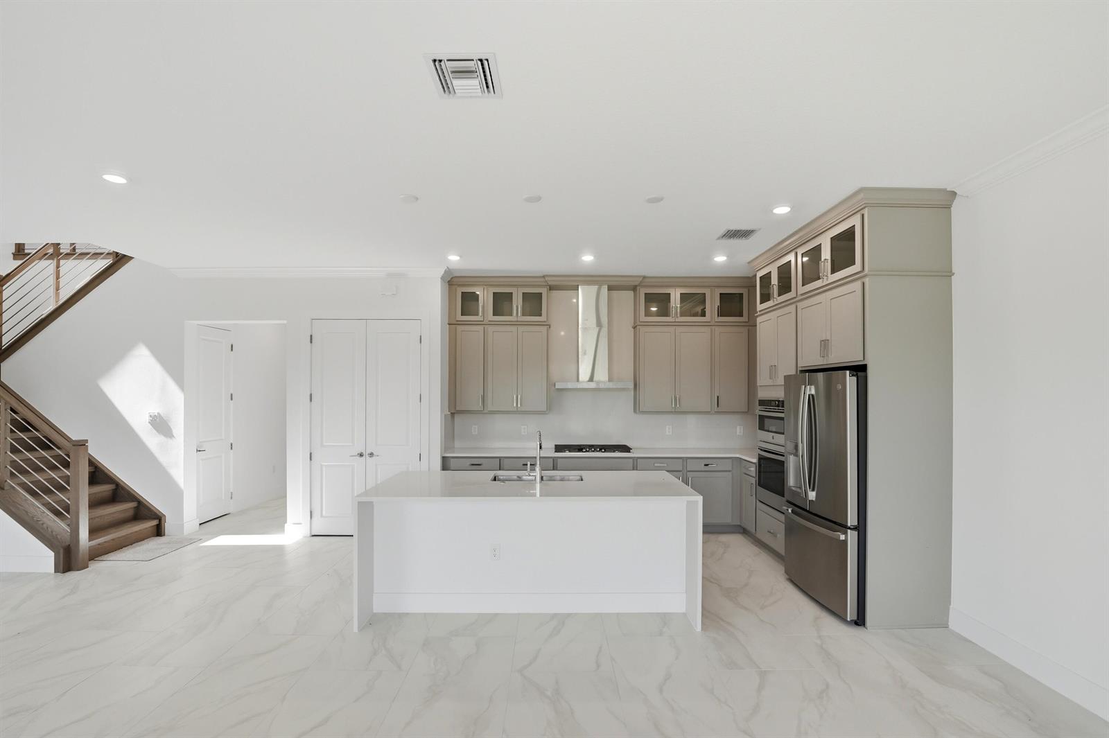 A modern kitchen features light-toned cabinetry, a white quartz island, and marble-look tile flooring — 1016 Raleigh Way, Wellington FL 33414, WELLINGTON, FL