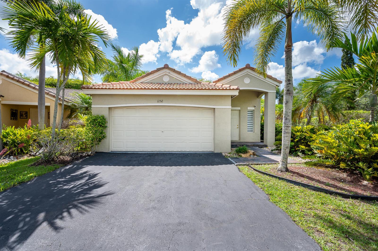 A single-story house with a beige stucco exterior, tile roof, and a two-car garage — 1252 Sabal Trail, Weston FL 33327, WESTON, FL