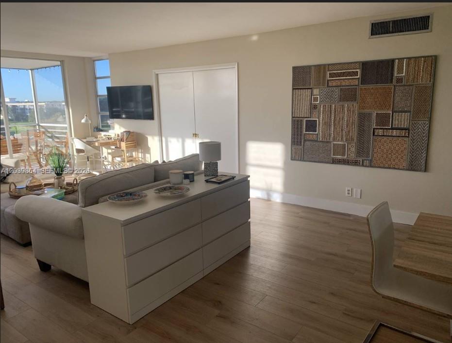 A living room features light wood flooring, a sofa with a console table, and wall art — 3520 Oaks Way # 607, Pompano Beach FL 33069, POMPANO BEACH, FL