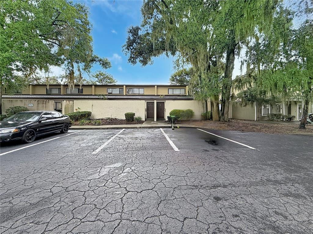 A two-story townhouse exterior with a cracked asphalt parking lot in the foreground — 2508 SW 35TH PLACE UNIT A6, GAINESVILLE, FL