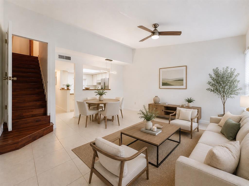 A living room and dining area feature light tile floors, wooden stairs, and neutral furniture — 2508 SW 35TH PLACE UNIT A6, GAINESVILLE, FL