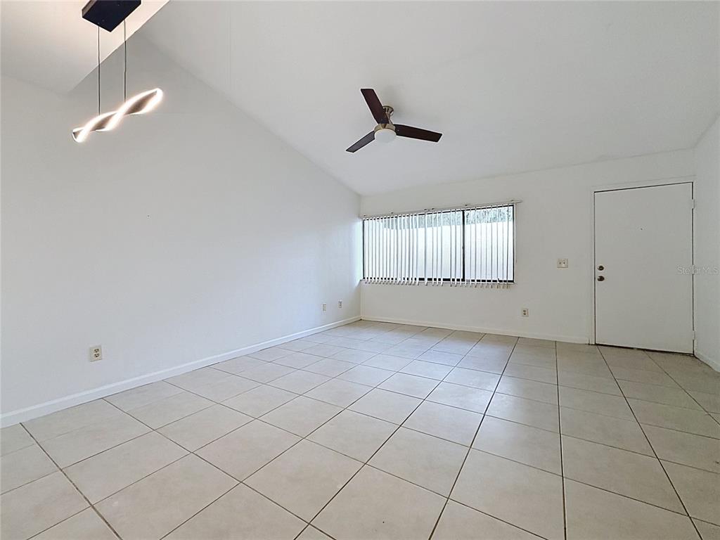 An empty room with white walls, tile flooring, a vaulted ceiling, and a ceiling fan — 2508 SW 35TH PLACE UNIT A6, GAINESVILLE, FL