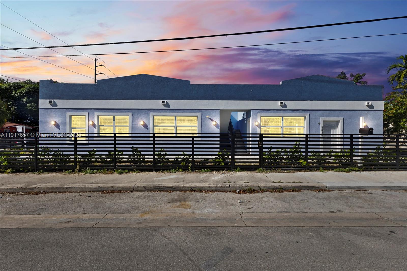 A single-story blue building with a black horizontal fence stands behind a concrete sidewalk — 305 NW 58th St, Miami FL 33127, MIAMI, FL