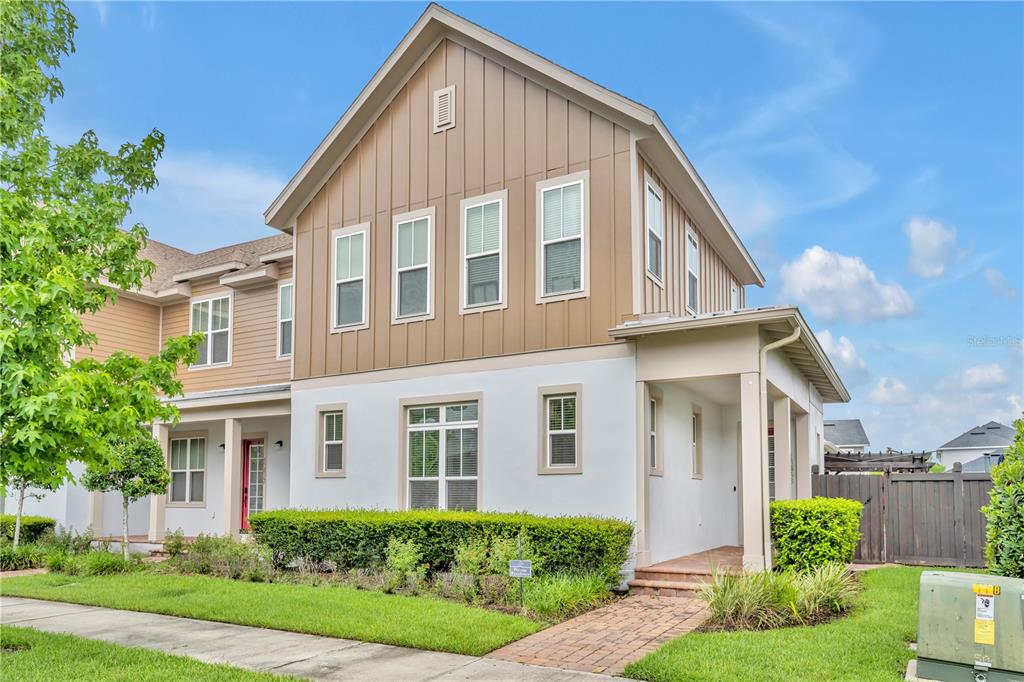 A two-story house with tan vertical siding, white stucco, and a brick walkway — 13433 STODDART AVENUE, ORLANDO, FL
