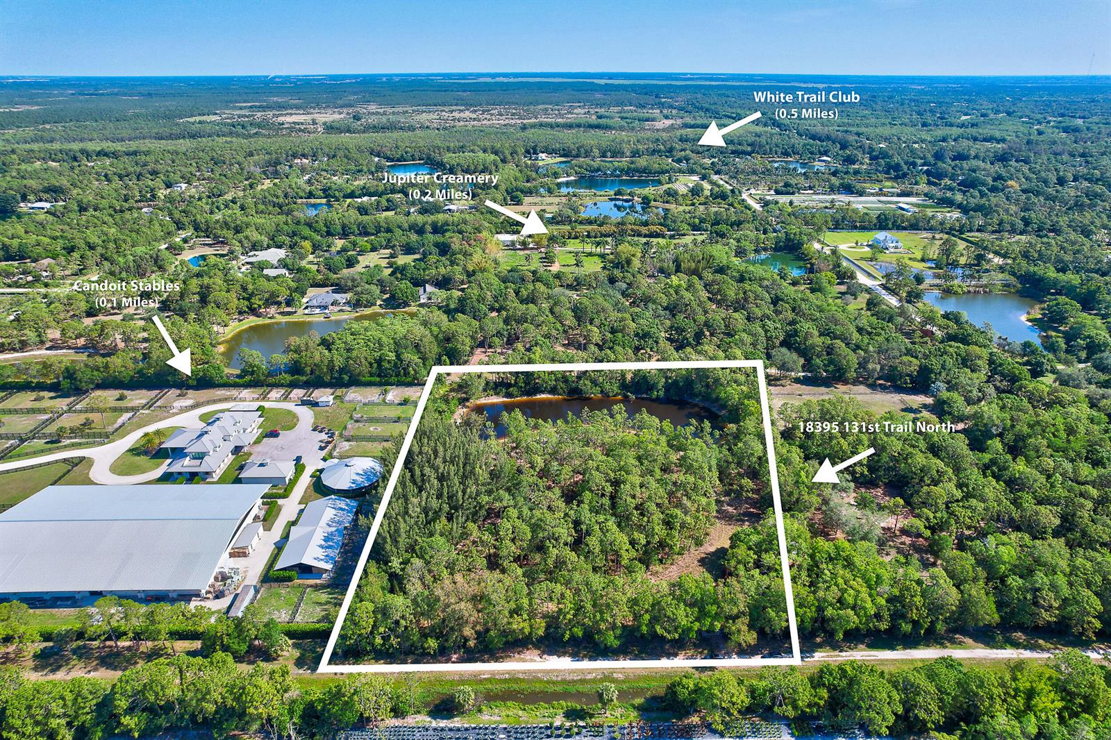 An aerial view shows a wooded lot with a pond next to a large equestrian facility — 18395 131st Trail N, Jupiter FL 33478, JUPITER, FL