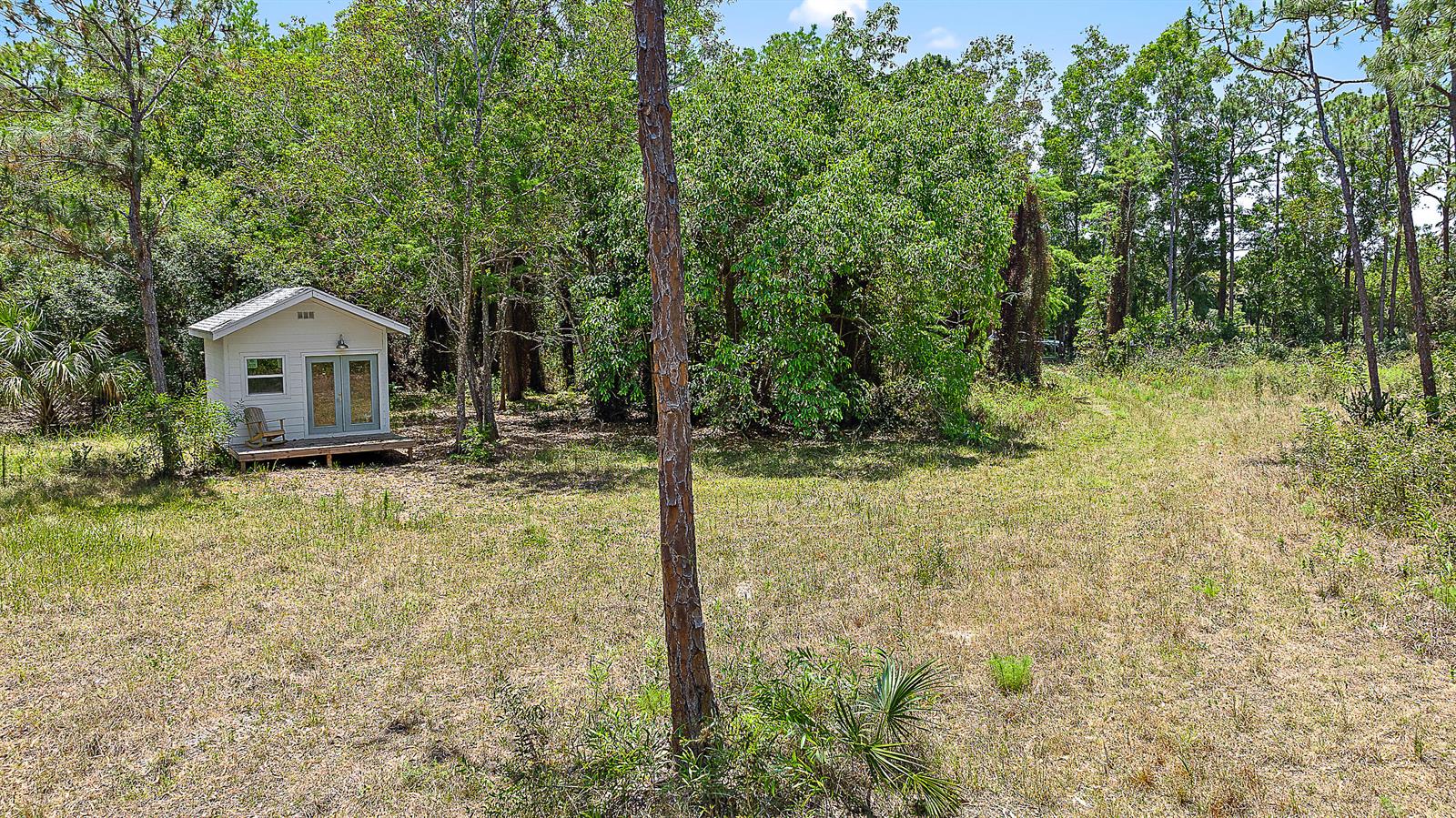 A small white shed with a wooden deck sits in a grassy, wooded lot — 18395 131st Trail N, Jupiter FL 33478, JUPITER, FL