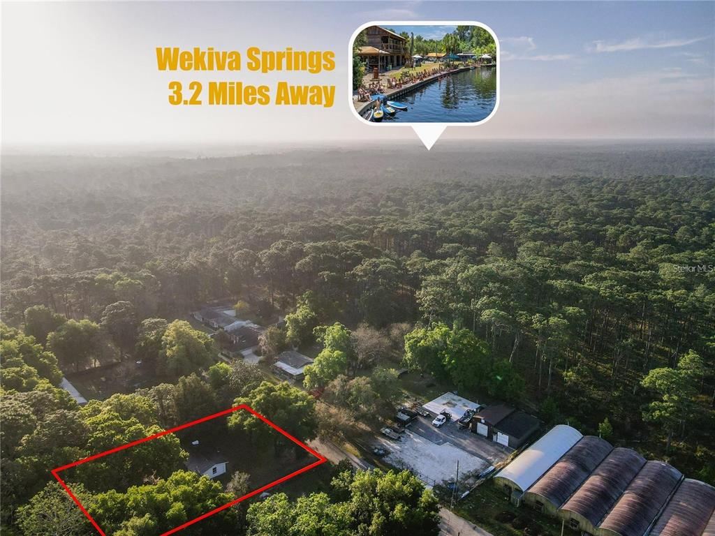 This aerial view shows a residential lot outlined in red near a forested area — 107 EARLS LANE, APOPKA, FL