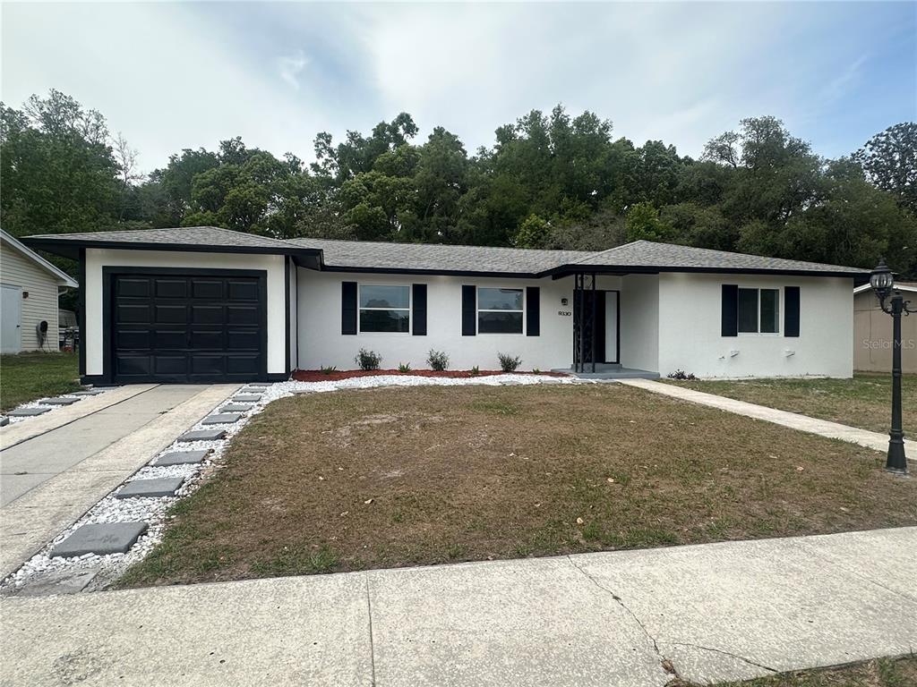 A single-story house with a white exterior, black trim, and a black garage door — 9330 N CITRUS SPRINGS BOULEVARD, CITRUS SPRINGS, FL